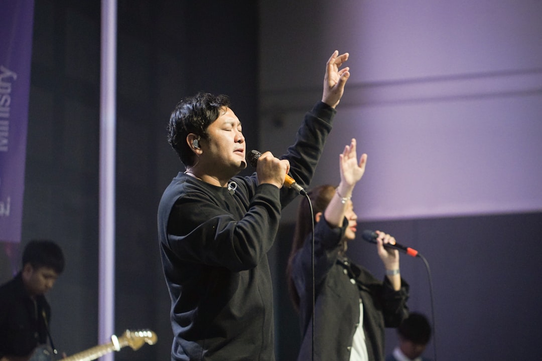 man-singing-with-hands-raised-on-stage-hzsmsopmhe